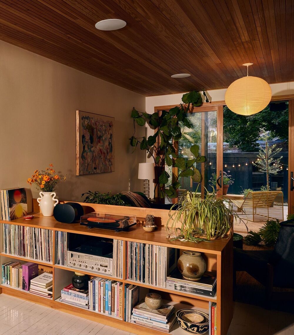 Living and dining area with a warm wood ceiling and flush-mounted in-ceiling speakers